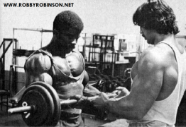 ROBBY_ROBINSON_1975_DENNY_GABLE_PUMPING_IRON_FILMING_PHOTO_SHOOT_TRAINING_POSING_WORKOUT_ARMS_STANDING_BARBELL_CURLS_01.png